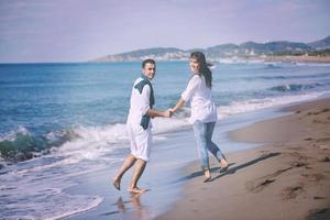 Lycklig ung par ha roligt på skön strand foto