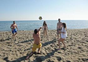 ung människor grupp ha roligt och spela strand volleyboll foto