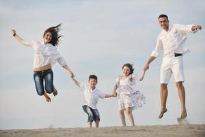 Lycklig ung familj ha roligt på strand foto