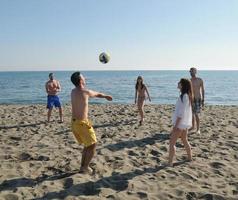 ung människor grupp ha roligt och spela strand volleyboll foto