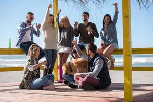 grupp av vänner har roligt på höst dag på strand foto