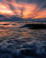 hav vågor under färgglad himmel vid solnedgången foto