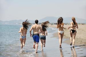 Lycklig ung människor grupp ha roligt på strand foto