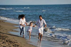 Lycklig ung familj ha roligt på strand foto