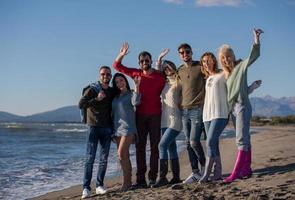 porträtt av vänner har roligt på strand under höst dag foto