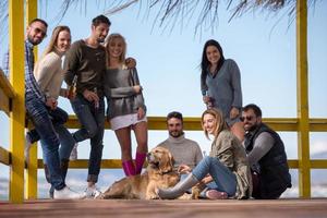 grupp av vänner har roligt på höst dag på strand foto