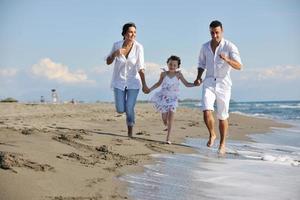 Lycklig ung familj ha roligt på strand foto