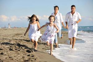 Lycklig ung familj ha roligt på strand foto