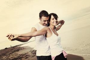 Lycklig ung par ha roligt på skön strand foto
