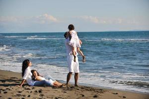 Lycklig ung familj ha roligt på strand foto