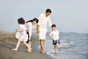 Lycklig ung familj ha roligt på strand foto