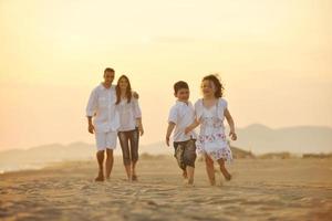 Lycklig ung familj ha roligt på strand på solnedgång foto