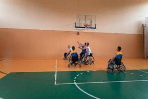 Inaktiverad krig veteraner blandad lopp och ålder basketboll lag i rullstolar spelar en Träning match i en sporter Gym hall. handikappade människor rehabilitering och inkludering begrepp foto