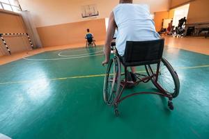 Inaktiverad krig veteraner blandad lopp och ålder basketboll lag i rullstolar spelar en Träning match i en sporter Gym hall. handikappade människor rehabilitering och inkludering begrepp foto