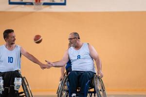 en team av krig veteraner i rullstolar spelar basketboll, fira poäng vann i en spel. hög fem begrepp foto