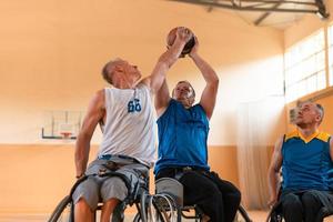 Inaktiverad krig veteraner blandad lopp och ålder basketboll lag i rullstolar spelar en Träning match i en sporter Gym hall. handikappade människor rehabilitering och inkludering begrepp foto