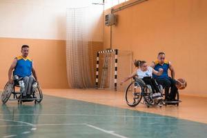 Inaktiverad krig veteraner blandad lopp och ålder basketboll lag i rullstolar spelar en Träning match i en sporter Gym hall. handikappade människor rehabilitering och inkludering begrepp foto