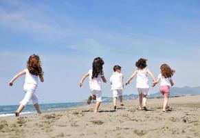 glad barn grupp som leker på stranden foto