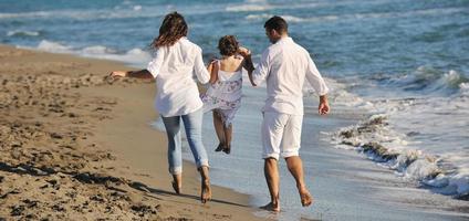 Lycklig ung familj ha roligt på strand foto