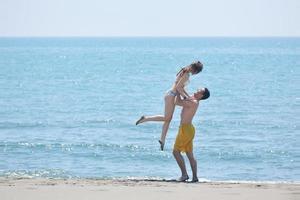 Lycklig ung par ha romantisk tid på strand foto