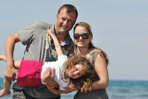 Lycklig ung familj ha roligt på strand foto