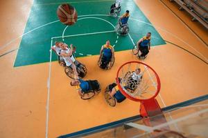 Inaktiverad krig eller arbete veteraner blandad lopp och ålder basketboll lag i rullstolar spelar en Träning match i en sporter Gym hall. handikappade människor rehabilitering och inkludering begrepp. foto