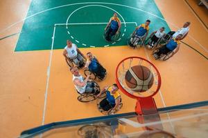 Inaktiverad krig eller arbete veteraner blandad lopp och ålder basketboll lag i rullstolar spelar en Träning match i en sporter Gym hall. handikappade människor rehabilitering och inkludering begrepp. foto