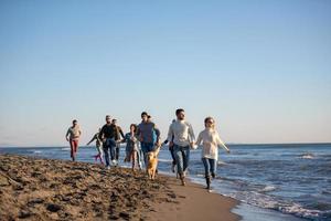 grupp av vänner löpning på strand under höst dag foto