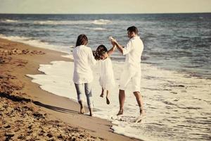 Lycklig ung familj ha roligt på strand foto