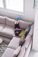 liten flicka använder sig av en smartphone på de soffa på Hem foto