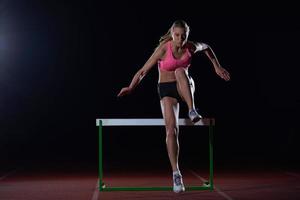 kvinna idrottare Hoppar över en hinder foto