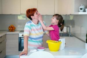 rolig liten flicka hjälpare spelar med deg på hans händer inlärning till knåda hjälper vuxen mamma i de kök, Lycklig söt bebis dotter och förälder mamma ha roligt matlagning småkakor. foto
