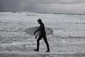 arktisk surfare gående förbi strand efter surfing foto