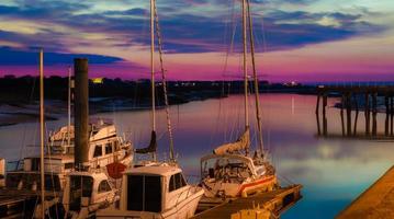 segelbåtar dockade på marin i vacker solnedgång