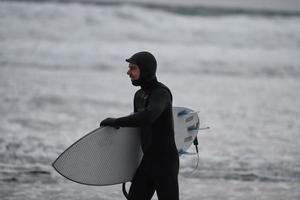 arktisk surfare gående förbi strand efter surfing foto