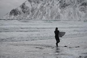 arktisk surfare gående förbi strand efter surfing foto