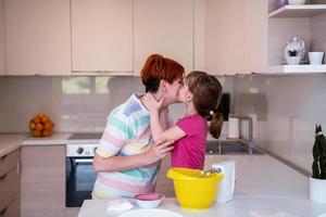 rolig liten flicka hjälpare spelar med deg på hans händer inlärning till knåda hjälper vuxen mamma i de kök, Lycklig söt bebis dotter och förälder mamma ha roligt matlagning småkakor. foto