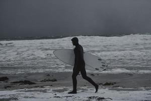 arktisk surfare gående förbi strand efter surfing foto