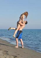 Lycklig ung par ha romantisk tid på strand foto