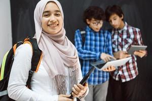 arabicum tonåringar team, studenter grupp arbetssätt tillsammans på bärbar dator och läsplatta dator uppkopplad klassrum utbildning begrepp foto