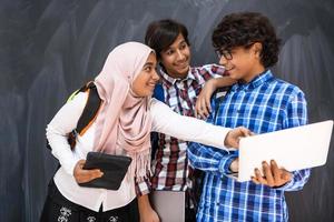 arabicum tonåringar team, studenter grupp arbetssätt tillsammans på bärbar dator och läsplatta dator uppkopplad klassrum utbildning begrepp foto