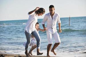 Lycklig ung familj ha roligt på strand foto