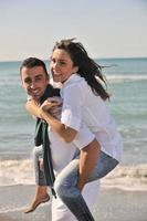 Lycklig ung par ha roligt på skön strand foto