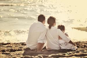 Lycklig ung familj ha roligt på strand foto