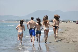 Lycklig ung människor grupp ha roligt på strand foto