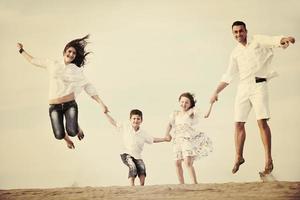 Lycklig ung familj ha roligt på strand foto