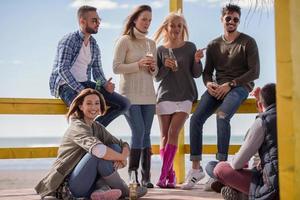 grupp av vänner har roligt på höst dag på strand foto