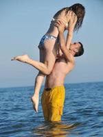 Lycklig ung par ha romantisk tid på strand foto