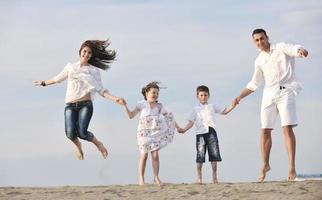 Lycklig ung familj ha roligt på strand foto