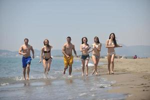 Lycklig människor grupp ha roligt och löpning på strand foto